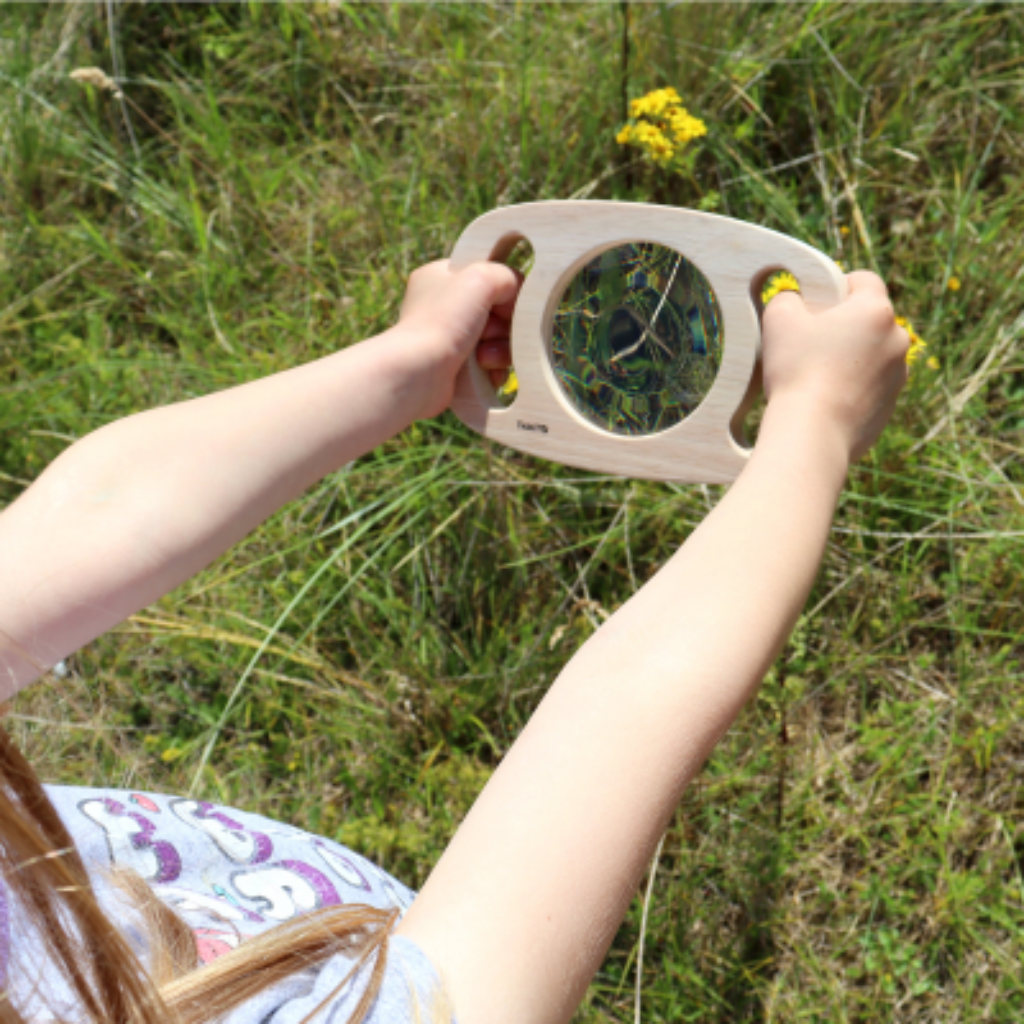 Auf einer Wiese, Kind hält Spiegel