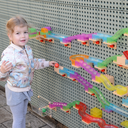 Kind spielt mit der Kugelbahn an der Wand