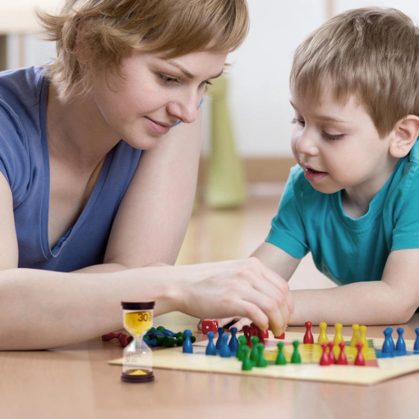 Mutter mit Kind spielen ein Spiel, Sanduhr im Vordergrund