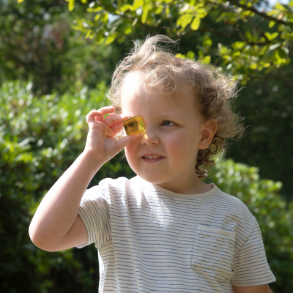 Kind schaut durch gelben Würfel