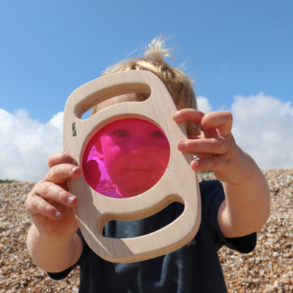 Kind schaut durch rosa Scheibe